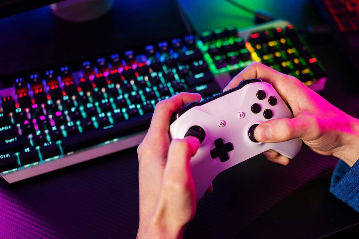 Close-up of hands holding a game controller in front of an RGB-lit mechanical keyboard