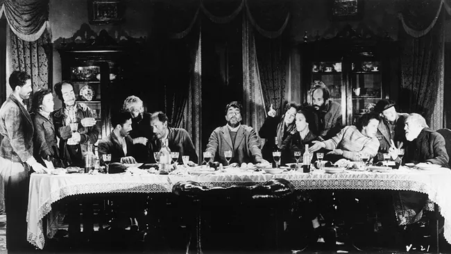 A black-and-white photo staged like The Last Supper, with a group seated around a long table